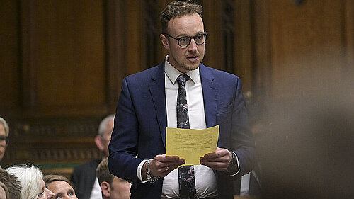 Adam standing up in Parliament